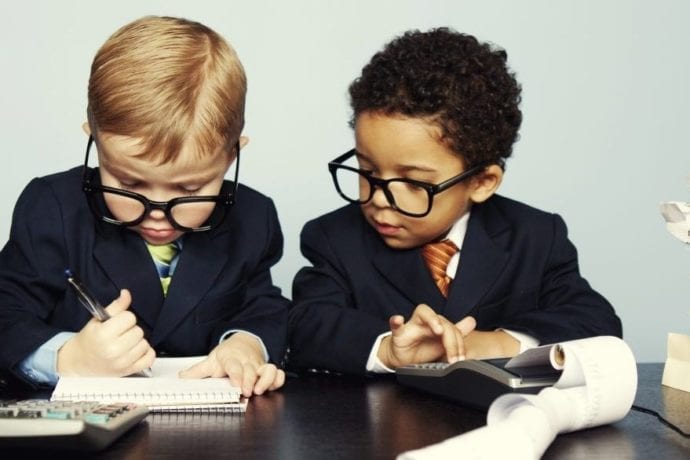 children in professional clothing looking at financial documents